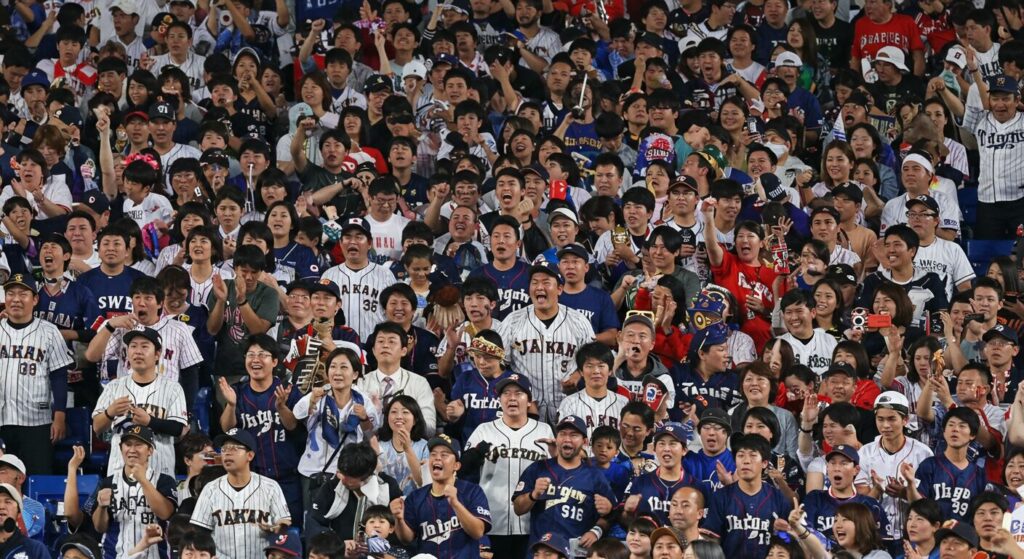 スーツ姿の女性政治家が執務室で熱狂的に野球観戦している様子