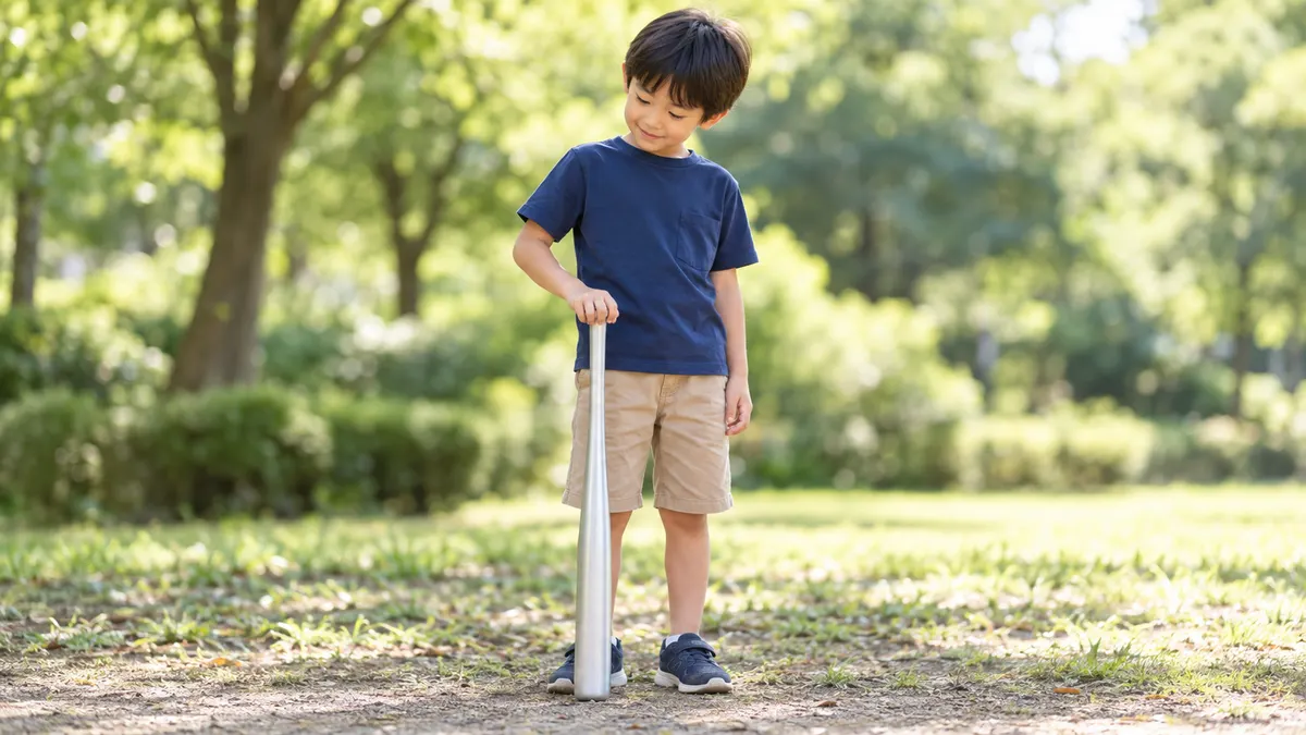 公園でバットを地面に立ててサイズを確かめる子のイメージ（生成AIによる画像）